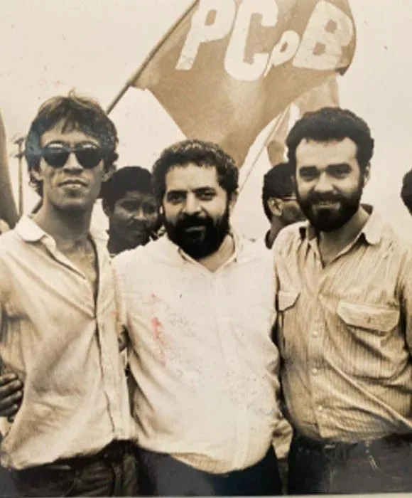 Daniel Almeida ao lado de companheiros sob a bandeira do PCdoB